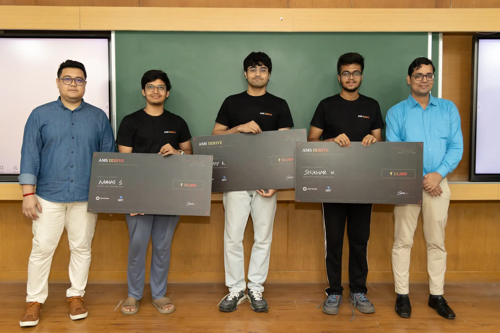 The three Derive '26 winners holding their prize cheques, flanked by organizers, IIT Bombay